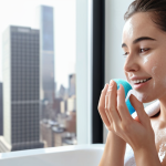 **

A modern, minimalist bathroom scene. Focus on a woman with healthy, glowing skin gently cleansing her face with a foaming cleanser. A bottle of low pH cleanser is visible, along with a soft towel. The background includes subtle hints of a city skyline visible through a frosted window. The overall tone is clean, bright, and focused on a healthy skincare routine.

**